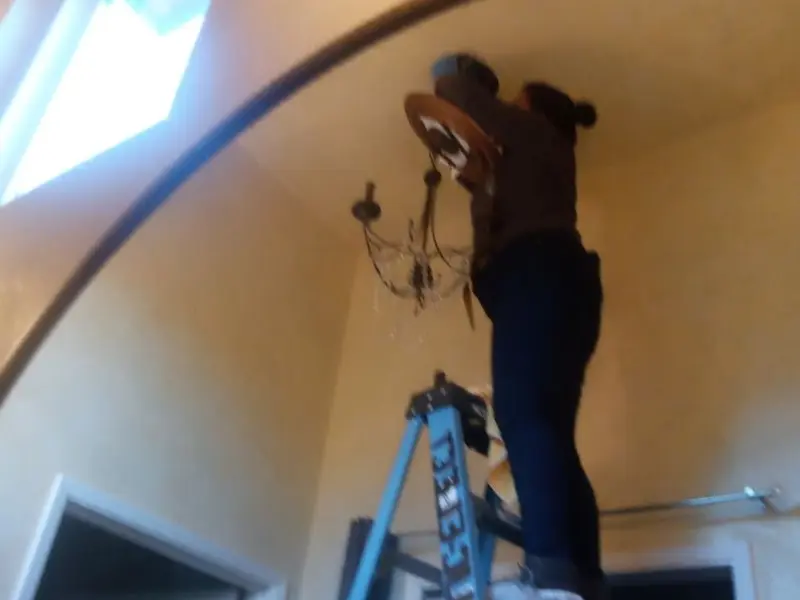 Electrician installing a chandelier in a Denton residence